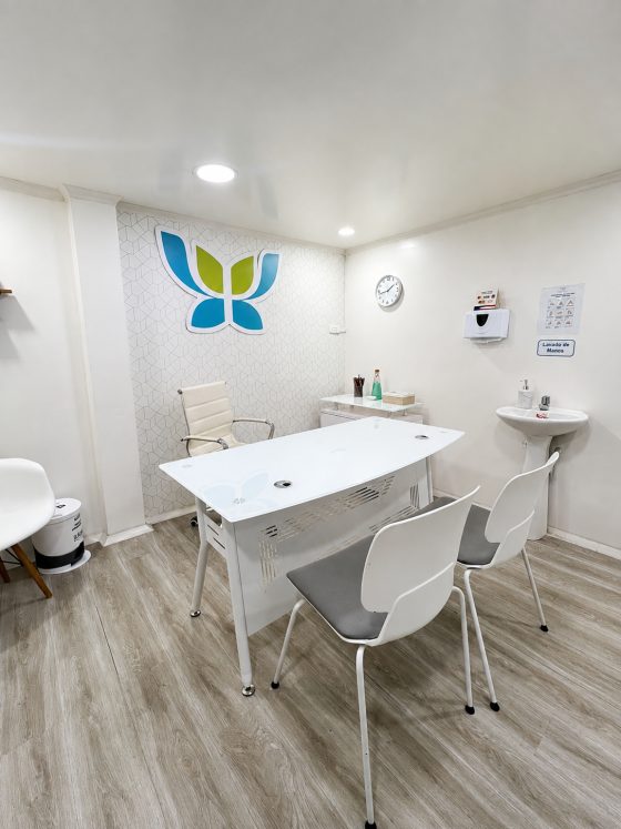 Mesa de trabajo del consultorio con material y reloj de pared