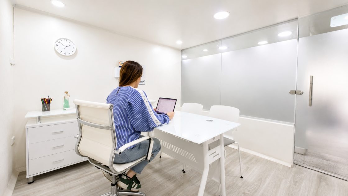 Terapeuta trabajando en el escritorio del consultorio, con la puerta de vidrio esmerilado al fondo